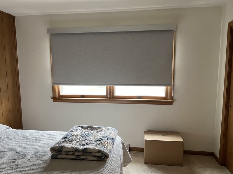 Dove grey roller shade half open in a Marietta guest bedroom