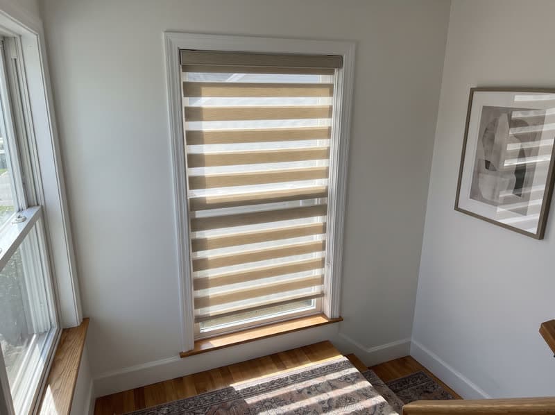 Tall sand zebra shade on a two-story stairwell window in Buford