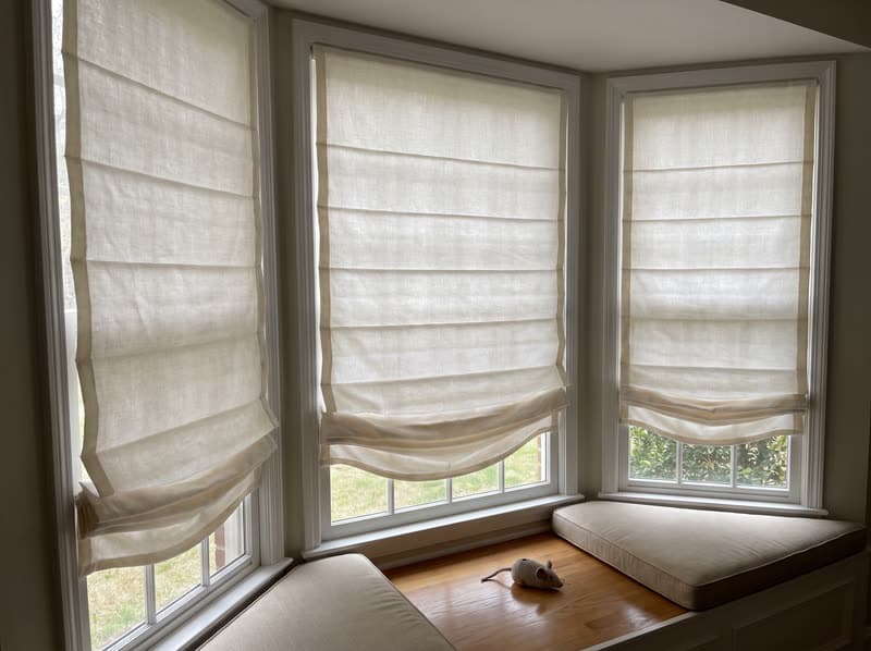 Relaxed roman shades across a bay window in a Marietta living room