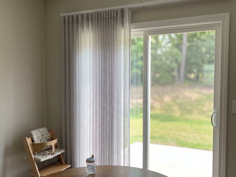 Grey vertical sheer dream curtain stacked to one side of a patio door in Buford