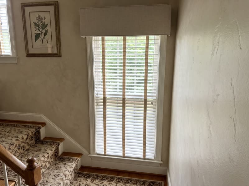 Faux wood blind on a stairwell landing window in a traditional two-storey house in Buford