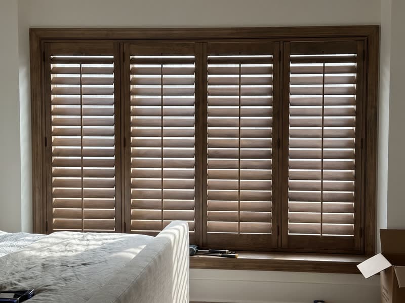 Wood shutters on a primary bedroom window in a modern farmhouse in Milton